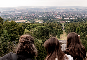 Die Hinterköpfe von drei jungen Frauen die von der Wilhelmshöhe nach Kassel schauen