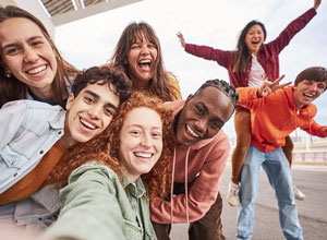Junge Menschen lachen und posieren fröhlich für ein Selfie in einer Gruppe.