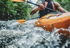 Eine Person im Kanu, die in wildem Gewässer paddelt